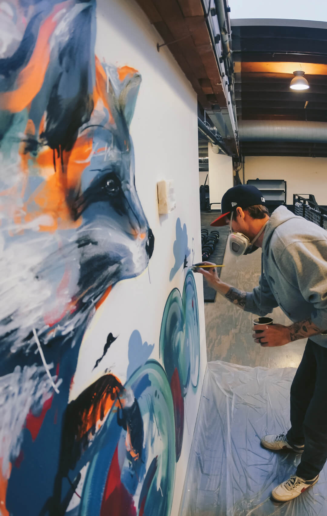 Man painting wolf on wall at indoor rock climbing gym