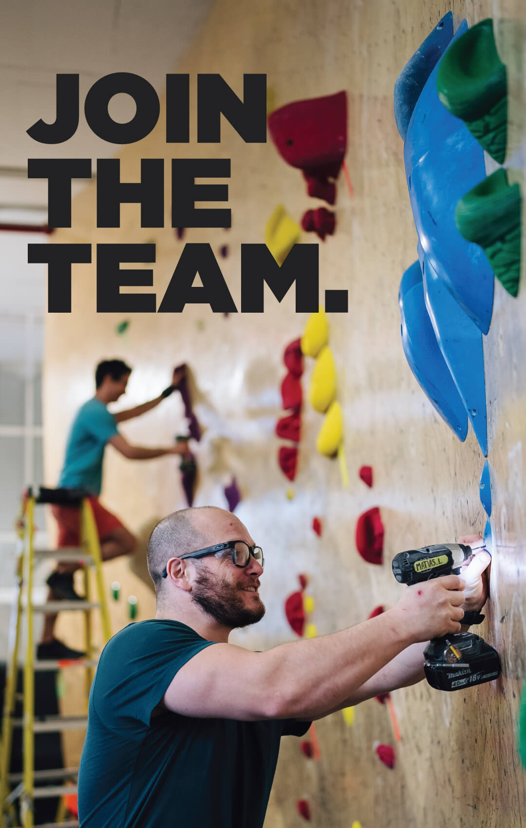 Join the team. - Man drilling fixture into indoor rock climbing wall