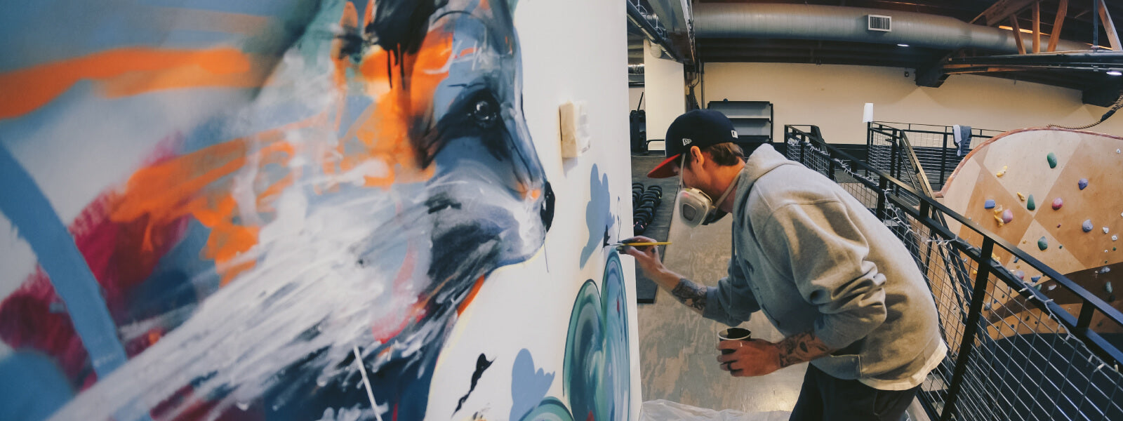 Man painting wolf on wall at indoor rock climbing gym